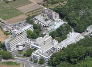 施設全体の空撮。複数棟の建物が緑地に囲まれた介護施設の鳥瞰図。