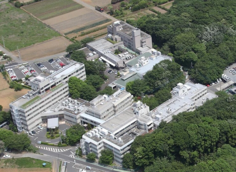 複数の建物群からなる介護施設の空撮。駐車場と緑地に囲まれた広大な敷地。